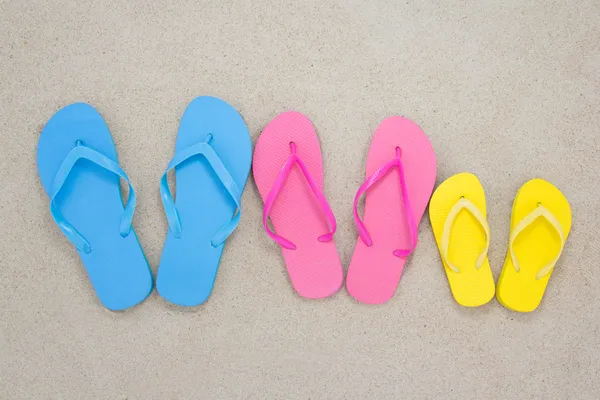 Colorful flip flops on sandy beach — Stock Photo, Image