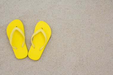 plaj kum üzerine sarı flip flop