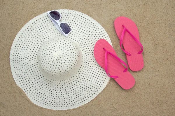 Roze flip-flops, zonnebril en hoed op zandstrand — Stockfoto