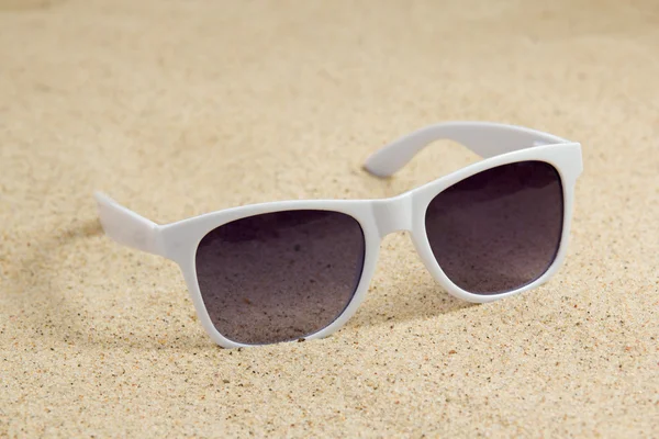 Kumlu sahilde beyaz trendy güneş gözlüğü — Stok fotoğraf