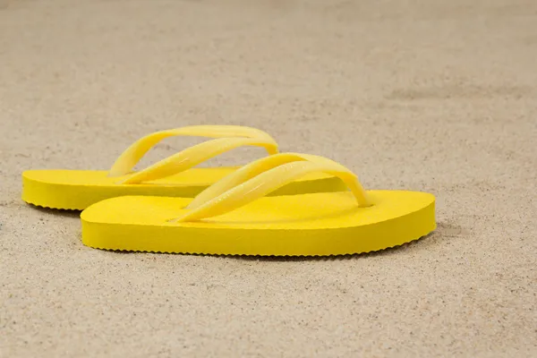 Pair of yellow flip flops on beach — Stock Photo, Image