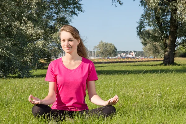 Mooie jonge vrouw zitten in park — Stockfoto