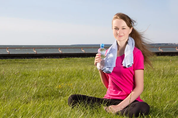 Vrouw zitten in park met handdoek en fles — Stockfoto