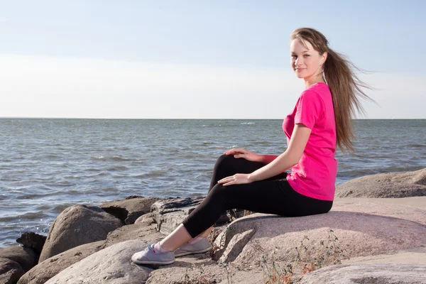 Mädchen in Rosa T-shirt sitzt in der Nähe von Meer — Stockfoto