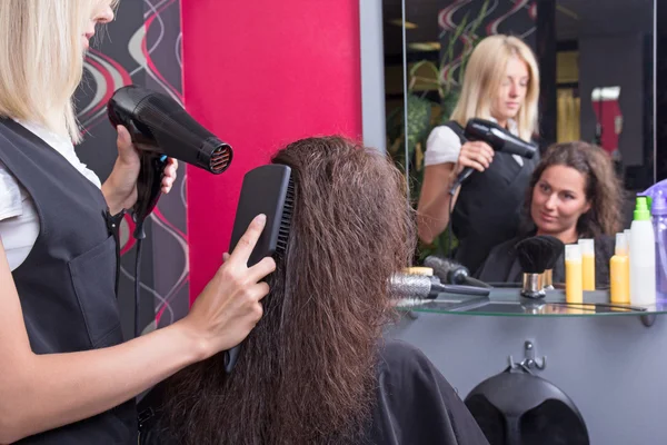 Cabeleireiro profissional com secador de cabelo e fem secagem escova de cabelo — Fotografia de Stock