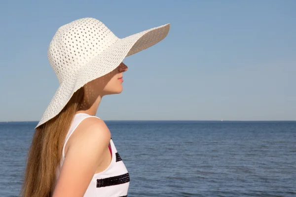 Vrouw in gestreepte jurk zittend op het strand — Stockfoto