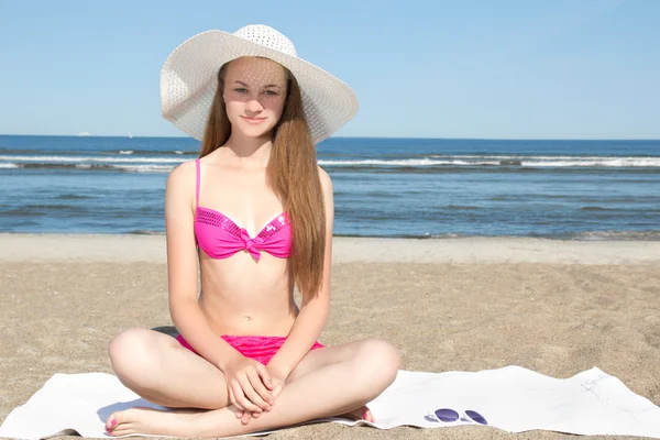 Hermosa adolescente en bikini rosa y sombrero blanco sentado en la b — Foto de Stock