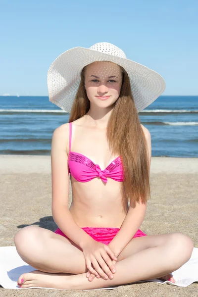 Aantrekkelijke vrouw in roze bikini zittend op het strand — Stockfoto