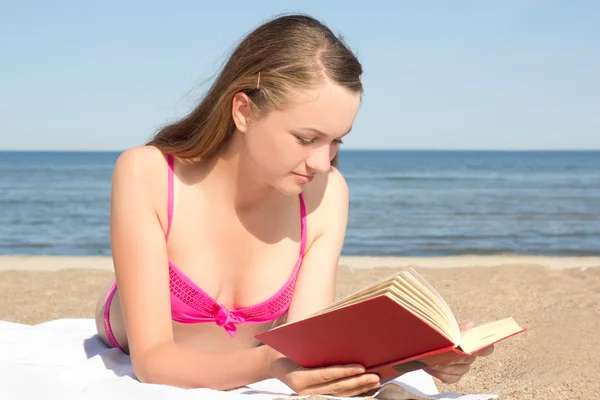 Mujer en bikini rosa lectura en la playa — Foto de Stock