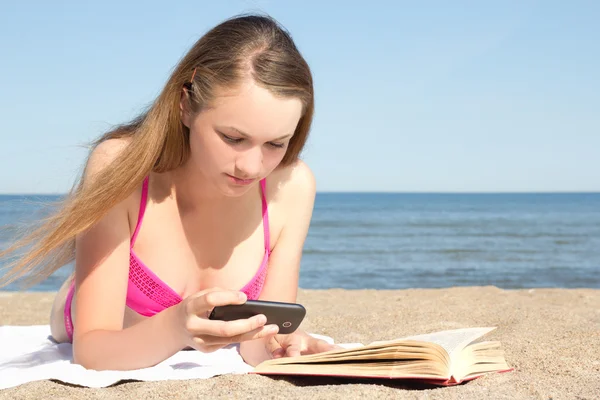 Rózsaszín bikini, mozgatható telefon és bo a strandon fekvő nő — Stock Fotó