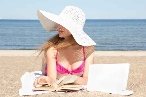 Female student with white laptop and book on the beach — Stok fotoğraf