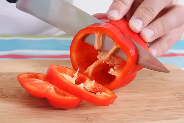 Hand with big knife cutting red pepper — Stock Photo, Image