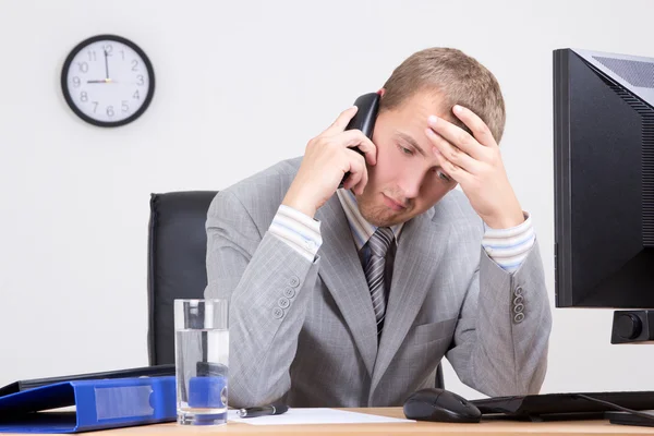 Tired businessman talking on phone in office — Stock Photo, Image