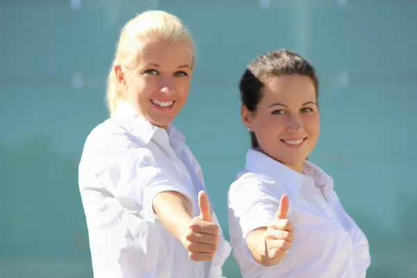 Két fiatal, vonzó üzleti nő hüvelykujj fel. a hangsúly a kezek — Stock Fotó