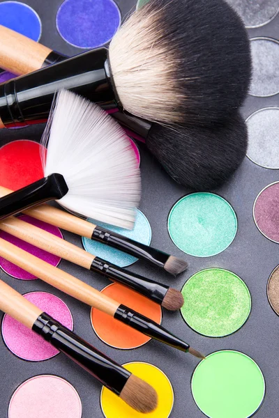Close up of make-up brushes and colorful eyeshadow palette over — Stock Photo, Image