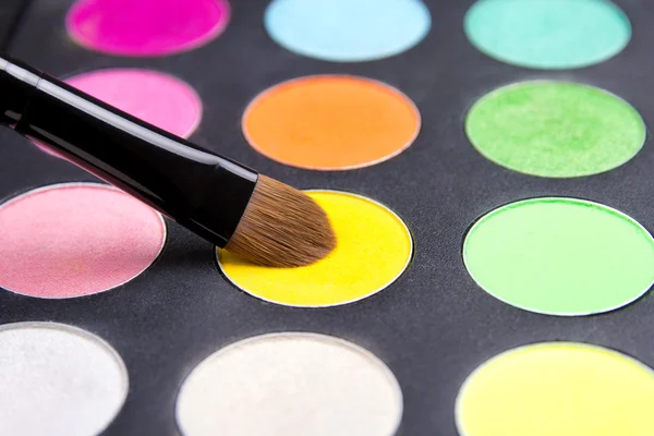 Make-up brush and colorful eyeshadow palette over black close up — Stock Photo, Image