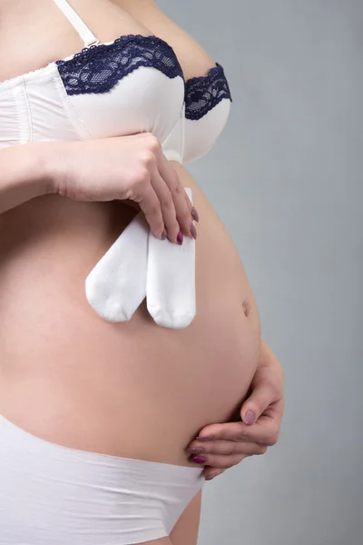 Cerca del vientre embarazado con cinta de regalo dorado y poco —  Fotos de Stock