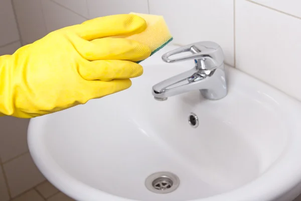 Hand in gele handschoen met spons in badkamer — Stockfoto