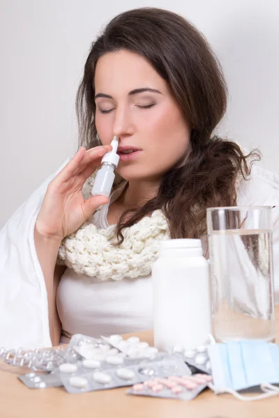 Młoda kobieta przy użyciu spray do nosa w jej salonie — Zdjęcie stockowe
