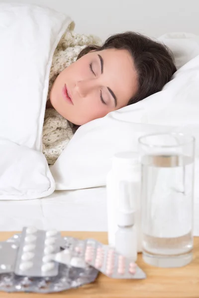 Jonge zieke vrouw slapen en pillen op de tafel — Stockfoto