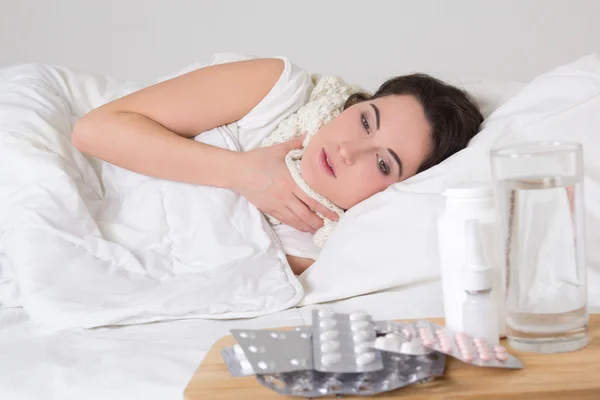 Joven mujer enferma y pastillas en la mesita de noche —  Fotos de Stock