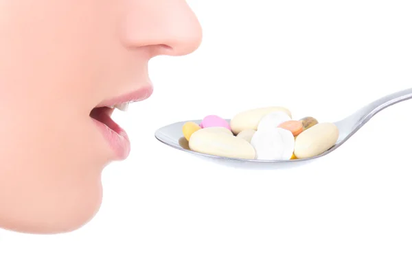 Close up of female mouth and pills on the spoon isolated on whit — Stock Photo, Image