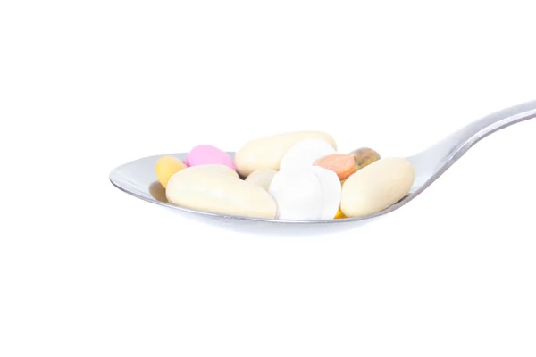 Close up of pills on the spoon isolated on white — Stock Photo, Image