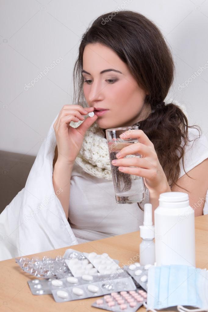 young ill woman taking pills in her living room