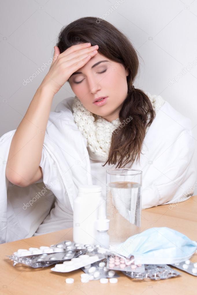 young woman with headache and pills on the table