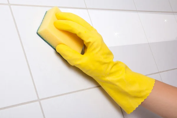 Hand in yellow glove cleaning tile wall — Stock Photo, Image