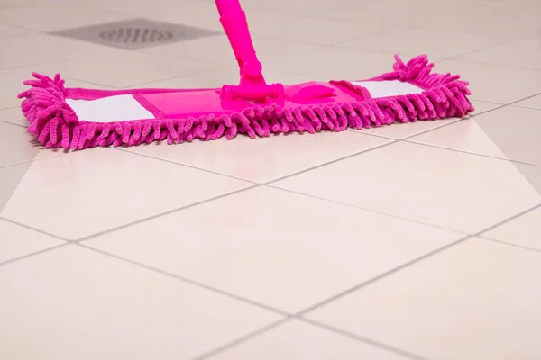 用粉红色的拖把清洁地板 — 图库照片
