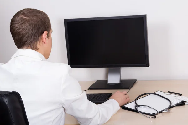 Jeune homme médecin sur ordinateur personnel au bureau — Photo