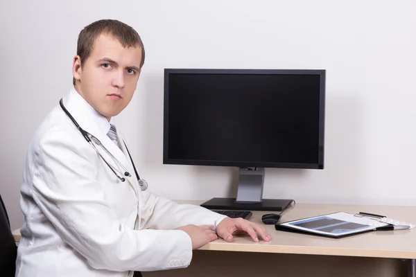 Joven doctor hombre sentado con computadora de oficina — Foto de Stock