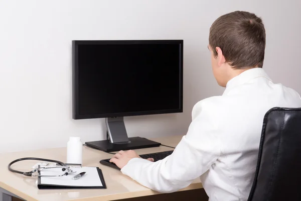 Jeune homme médecin travaillant avec l'ordinateur de bureau — Photo