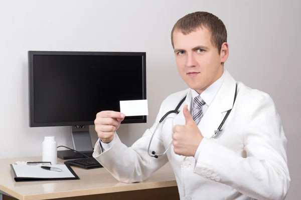 Giovane medico maschio rivelando business card e i pollici nell'ufficio — Foto Stock