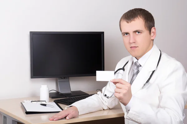 Young male doctor showing visiting card in office — Stock Photo, Image