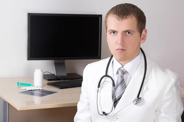 Young attractive doctor sitting in modern office — Stock Photo, Image