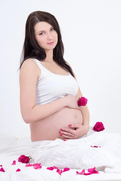 Jonge zwangere vrouw zitten met bloemen — Stockfoto