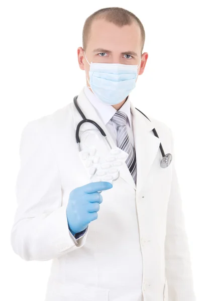 Portret van de jonge dokter in masker met pillen in hand geïsoleerd op — Stockfoto