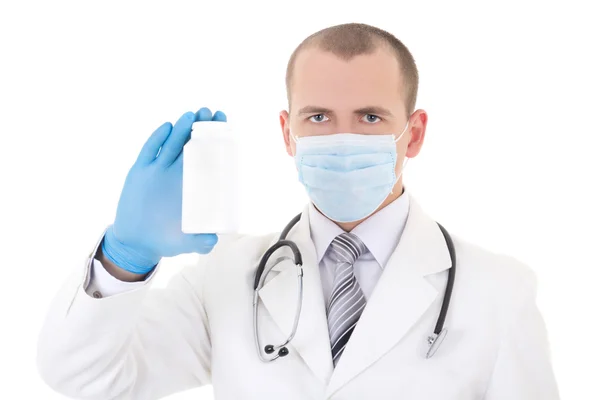 Giovane medico in maschera tenendo il flacone di pillole isolato su bianco — Foto Stock