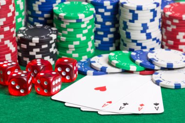 Poker fişleri, zar ve yeşil masada dört as