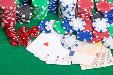 dadi, quattro assi, fiches da poker colorato e soldi su un feltro verde