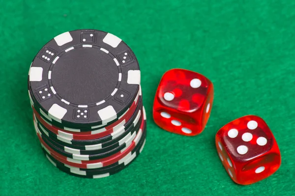 Чорно-червоні покерні чіпси та кістки на зеленому фетрі — стокове фото