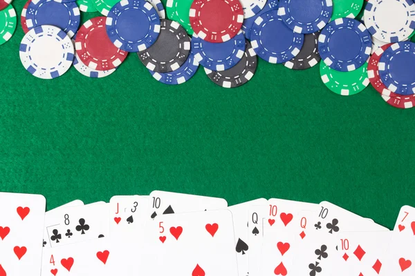 Poker fişleri ve kartları yeşil tablo arka plan üzerinde