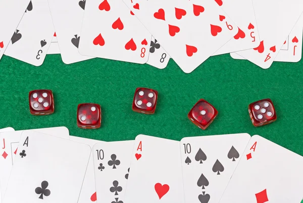 玩纸牌和绿色的桌子上的红色骰子的特写 — 图库照片