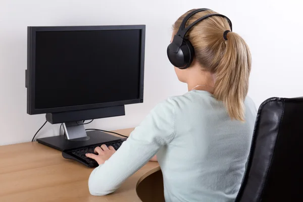 Jonge vrouw met behulp van een computer en muziek luisteren — Stockfoto
