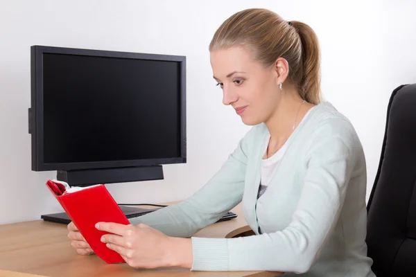 Jonge vrouw lezen boek in kantoor — Stockfoto