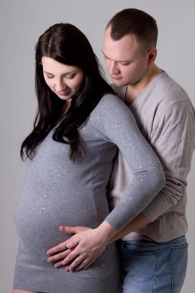 Junge schöne Paar warten Baby über grau — Stockfoto