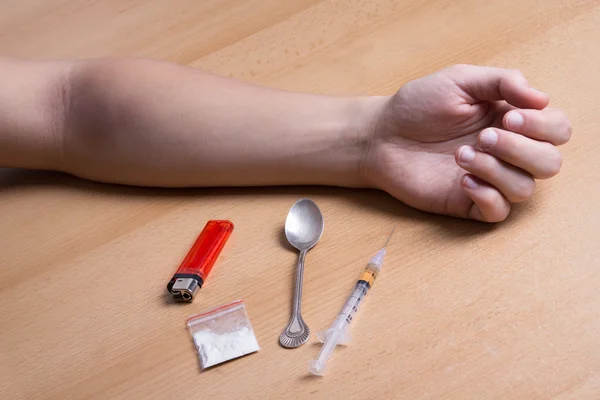 Close up van verslaafde de hand op de tafel met drugs — Stockfoto