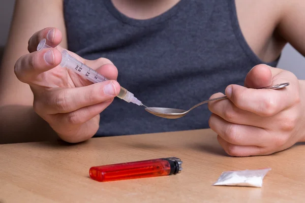 Man verslaafd aan drugs nemen een dosis van heroïne uit een lepel — Stockfoto
